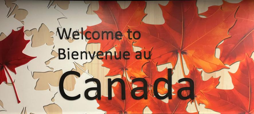 Welcome to Canada billboard with red and orange maple leaves