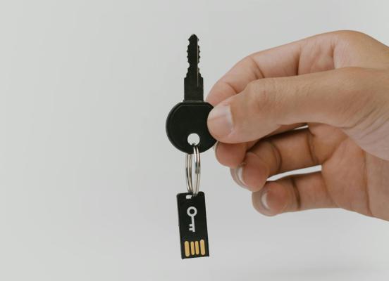 Hand holding a key, with a computer chip suspended from the key