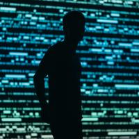 Surveillance, illustrated by the silhouette of a man in front of a data wall