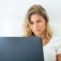 Woman looking at a computer, with a expression of worry on her face