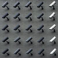 A grid of 35 surveillance cameras mounted on a wall and pointing to the lower left